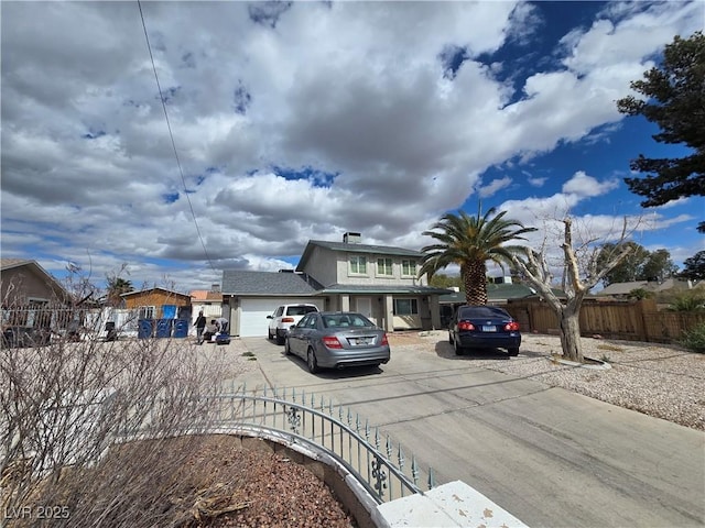 view of front of home with concrete driveway and fence