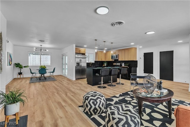 living room with recessed lighting, baseboards, visible vents, and light wood-type flooring