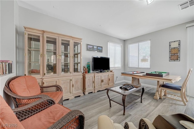 living room featuring light wood-style floors, visible vents, and baseboards