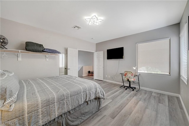 bedroom with visible vents, baseboards, and wood finished floors