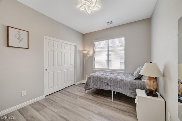 bedroom featuring light wood finished floors, visible vents, and baseboards