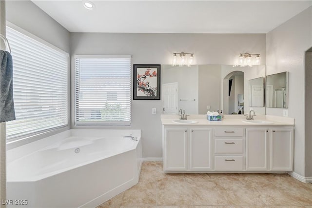 full bath featuring a bath, double vanity, baseboards, and a sink