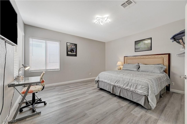 bedroom featuring wood finished floors, visible vents, and baseboards