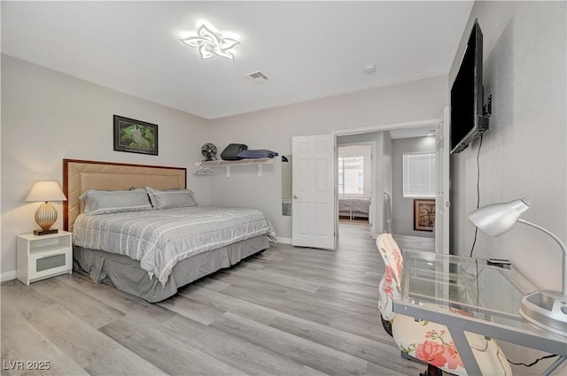 bedroom featuring light wood-type flooring, visible vents, and baseboards