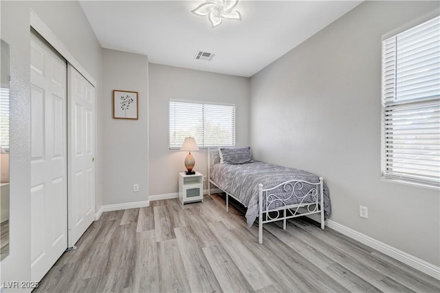 bedroom featuring wood finished floors, visible vents, a closet, and baseboards