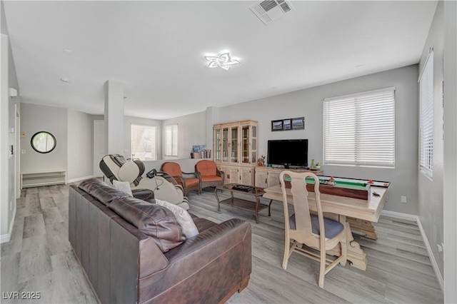 living room with light wood-style floors, visible vents, and baseboards