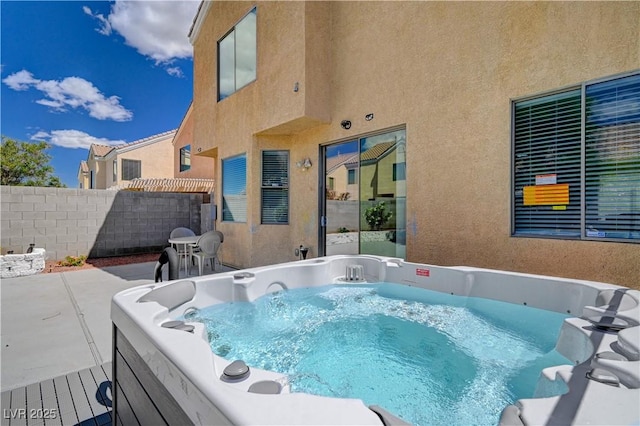 view of swimming pool featuring fence and a hot tub