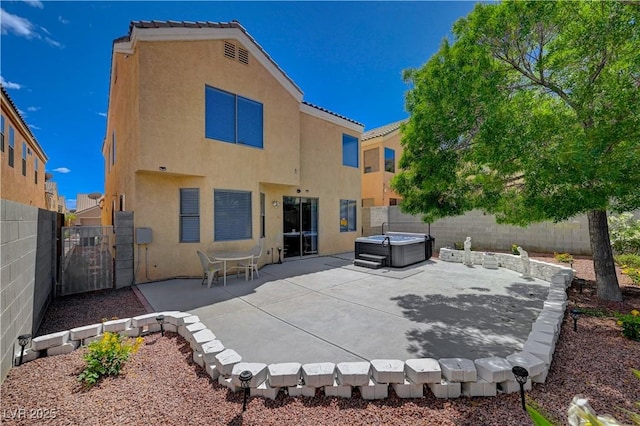 back of house featuring stucco siding, a patio, a fenced backyard, and a hot tub