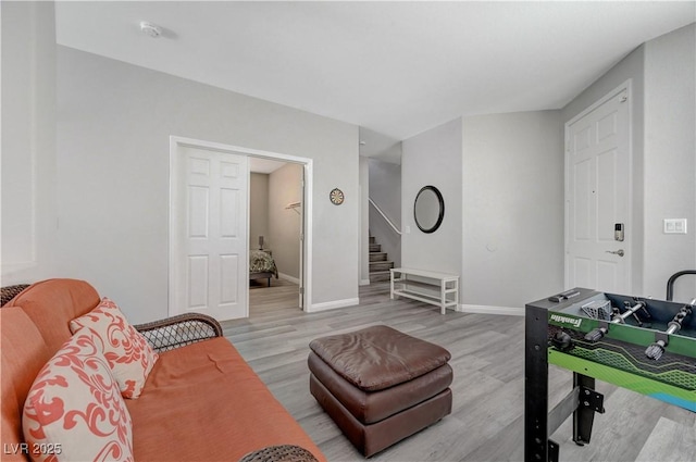 living area featuring stairs, baseboards, and wood finished floors