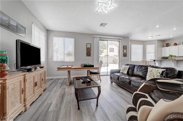 living room featuring visible vents, baseboards, and light wood finished floors