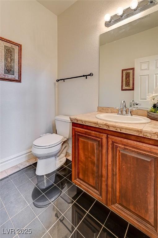 half bath featuring vanity, tile patterned floors, and toilet