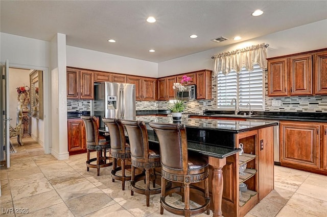 kitchen featuring visible vents, open shelves, a center island, stainless steel appliances, and a sink