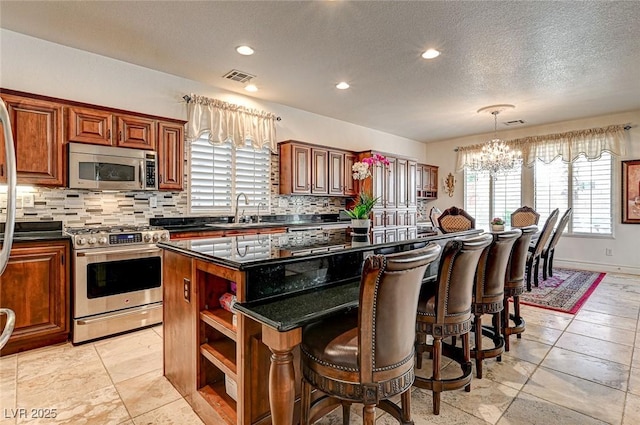 kitchen with visible vents, open shelves, a kitchen island, appliances with stainless steel finishes, and a sink