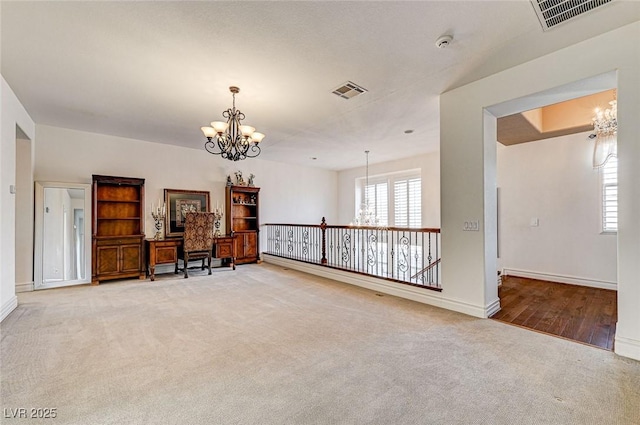 living area featuring light carpet, visible vents, baseboards, and an inviting chandelier