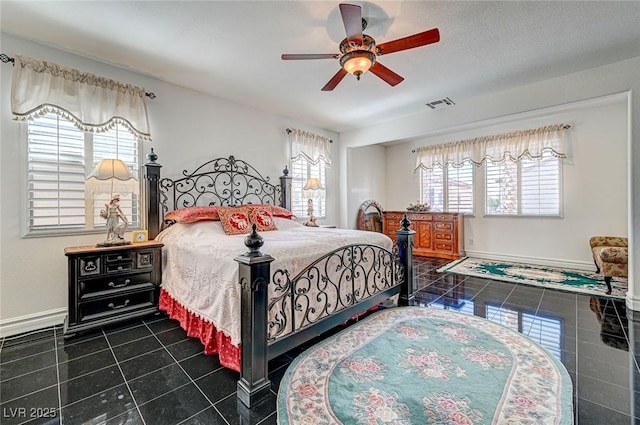 bedroom featuring a ceiling fan, dark tile patterned flooring, baseboards, and visible vents