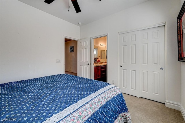 bedroom with connected bathroom, a ceiling fan, a closet, and light carpet