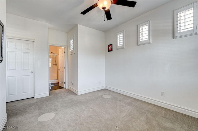 unfurnished bedroom featuring multiple windows, carpet flooring, baseboards, and connected bathroom