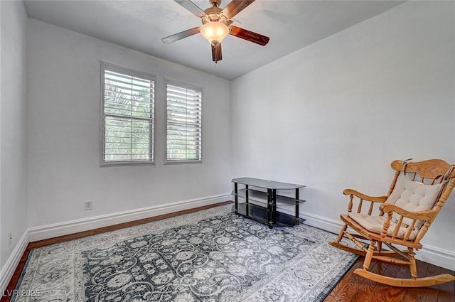 living area featuring ceiling fan, baseboards, and wood finished floors