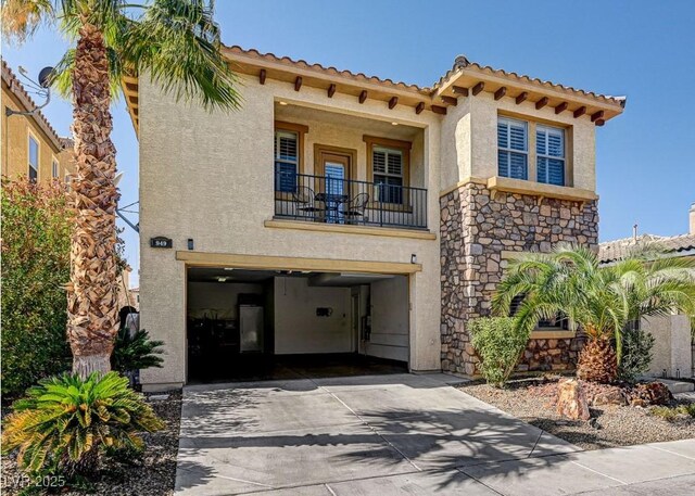 mediterranean / spanish-style house with stucco siding, driveway, stone siding, a garage, and a balcony