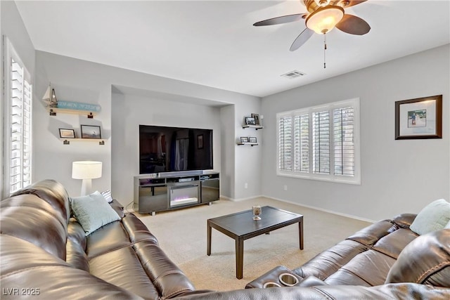 living area with visible vents, baseboards, carpet, and ceiling fan