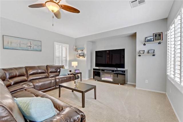 living room with visible vents, carpet floors, baseboards, and a ceiling fan