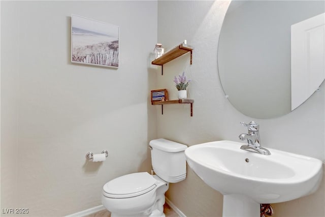 bathroom featuring a sink, baseboards, and toilet