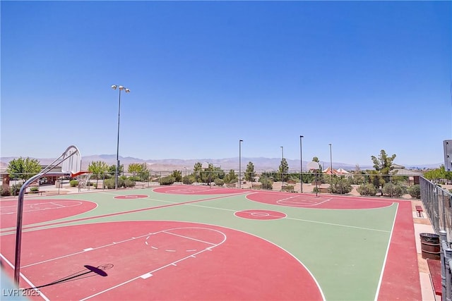 view of basketball court with a mountain view, community basketball court, and fence