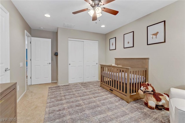 carpeted bedroom with a crib, recessed lighting, a closet, and ceiling fan