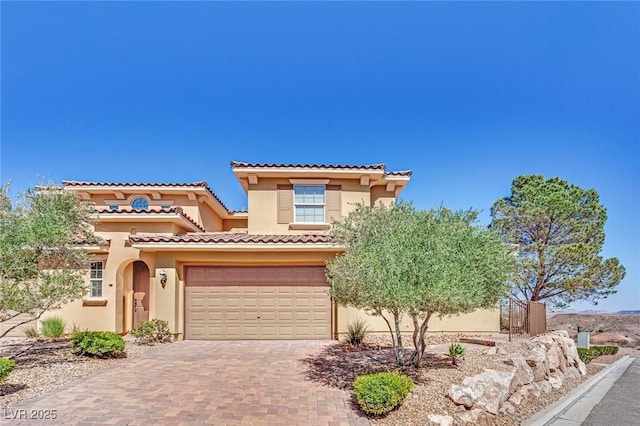 mediterranean / spanish-style house with a tiled roof, decorative driveway, an attached garage, and stucco siding