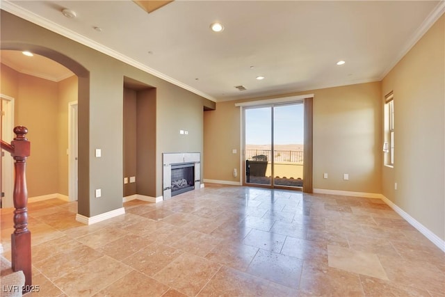 unfurnished living room with arched walkways, a fireplace, baseboards, and ornamental molding