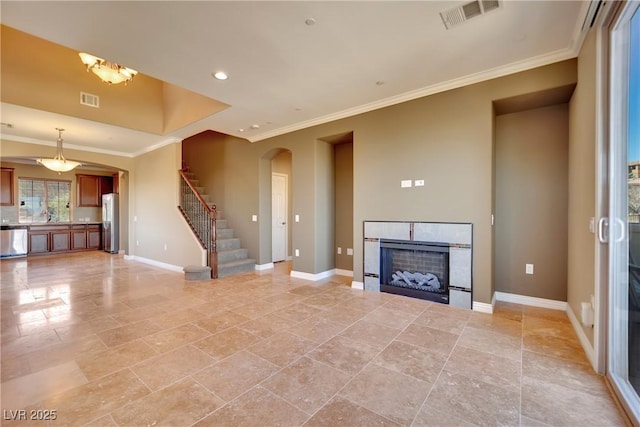 unfurnished living room with stairs, a fireplace, visible vents, and baseboards