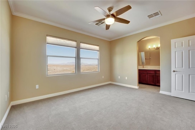 unfurnished bedroom featuring visible vents, baseboards, arched walkways, crown molding, and light colored carpet