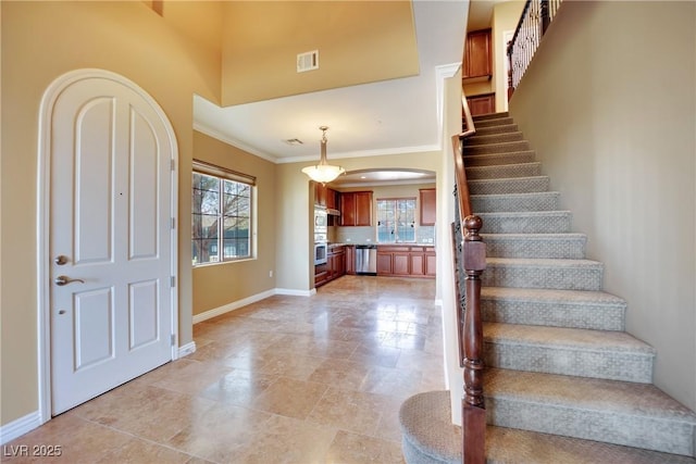 foyer featuring stairs, visible vents, baseboards, and ornamental molding