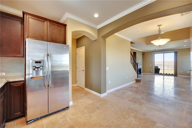 kitchen featuring arched walkways, stainless steel fridge, backsplash, and ornamental molding