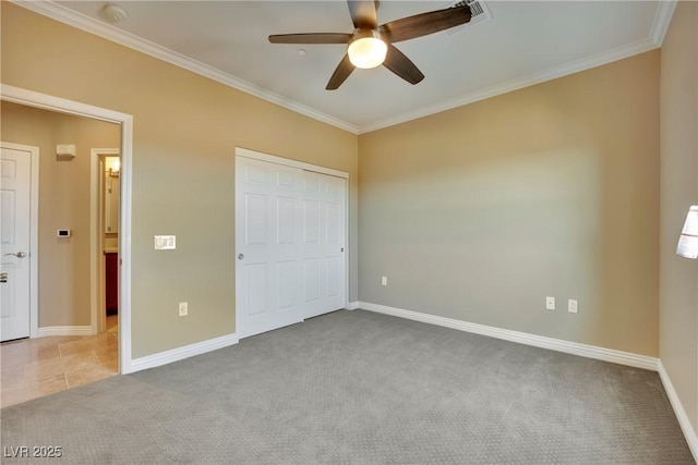 unfurnished bedroom featuring a closet, baseboards, crown molding, and carpet