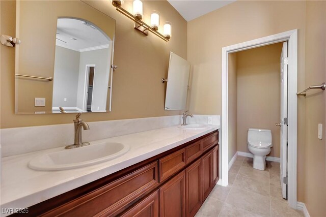 full bathroom featuring a sink, toilet, double vanity, and tile patterned floors