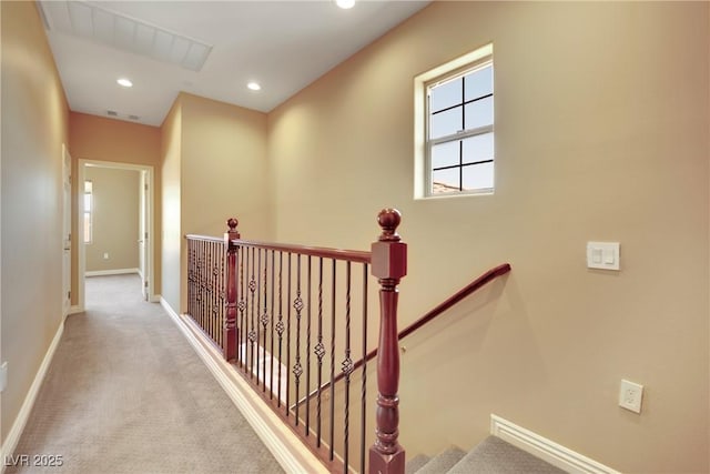 hallway featuring visible vents, baseboards, carpet floors, recessed lighting, and an upstairs landing