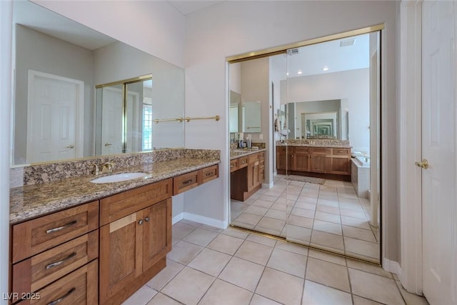 bathroom featuring a garden tub, baseboards, two vanities, a sink, and tile patterned floors