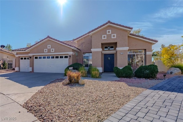 mediterranean / spanish home with stucco siding, a garage, driveway, and a tiled roof