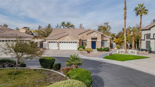 mediterranean / spanish home with a tiled roof, stucco siding, driveway, and a garage