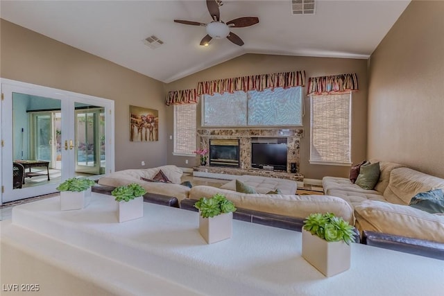 living area featuring visible vents, french doors, a glass covered fireplace, and vaulted ceiling