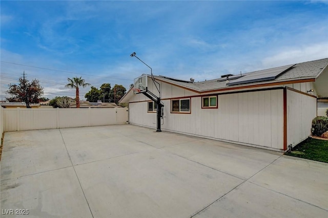 exterior space with a patio, fence, and roof mounted solar panels