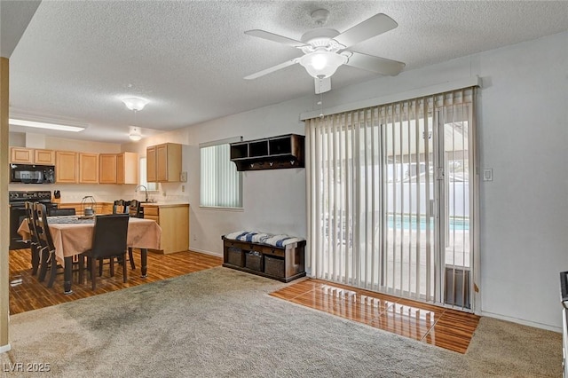 interior space featuring light colored carpet, a textured ceiling, and ceiling fan