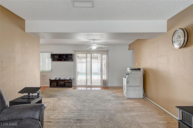 living area with a textured ceiling, visible vents, carpet, and a textured wall