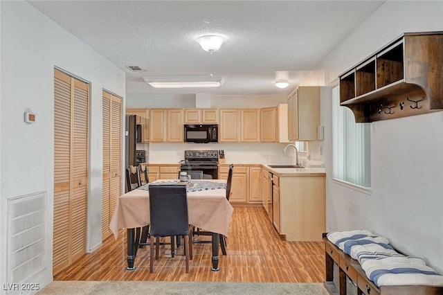 kitchen featuring visible vents, a sink, electric range oven, light brown cabinetry, and black microwave