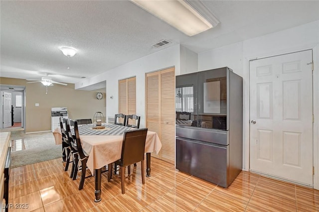 dining space featuring visible vents, a textured ceiling, and ceiling fan