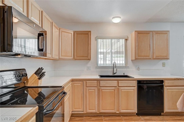 kitchen featuring a sink, black appliances, light countertops, and light brown cabinetry