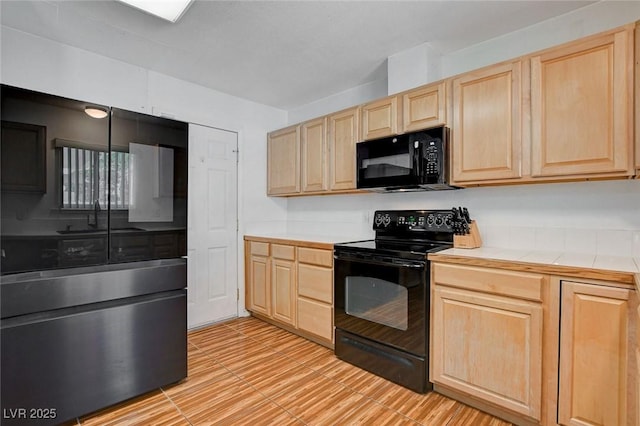 kitchen featuring black appliances, tile counters, and light brown cabinets