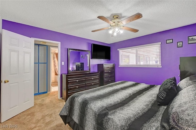 bedroom with ceiling fan, carpet flooring, and a textured ceiling