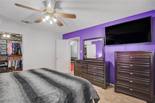 bedroom featuring visible vents, light carpet, a textured ceiling, a closet, and ceiling fan